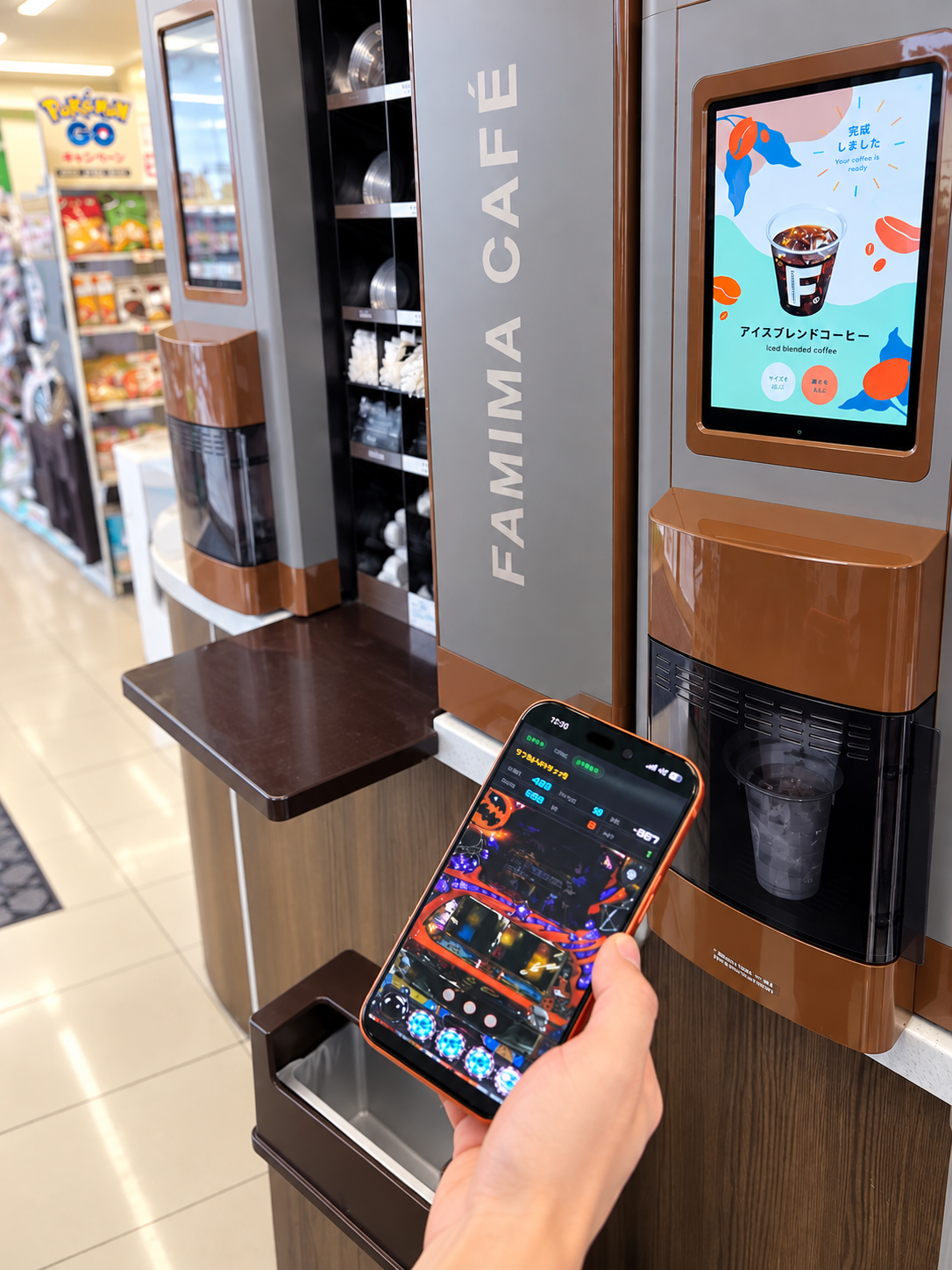 外出先（コンビニのコーヒーマシンの前）で、スマホから自宅の実機を遊んでいる様子